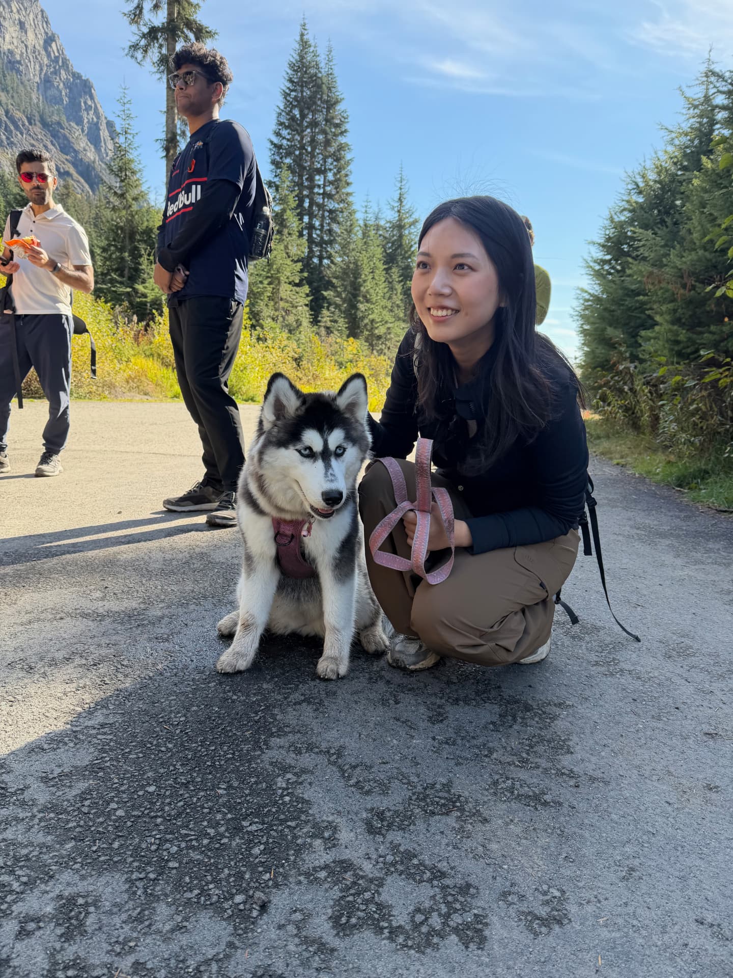 A Foster MBA classmate crouches beside Husky puppy Cove near Alpental after the Source Lake hike